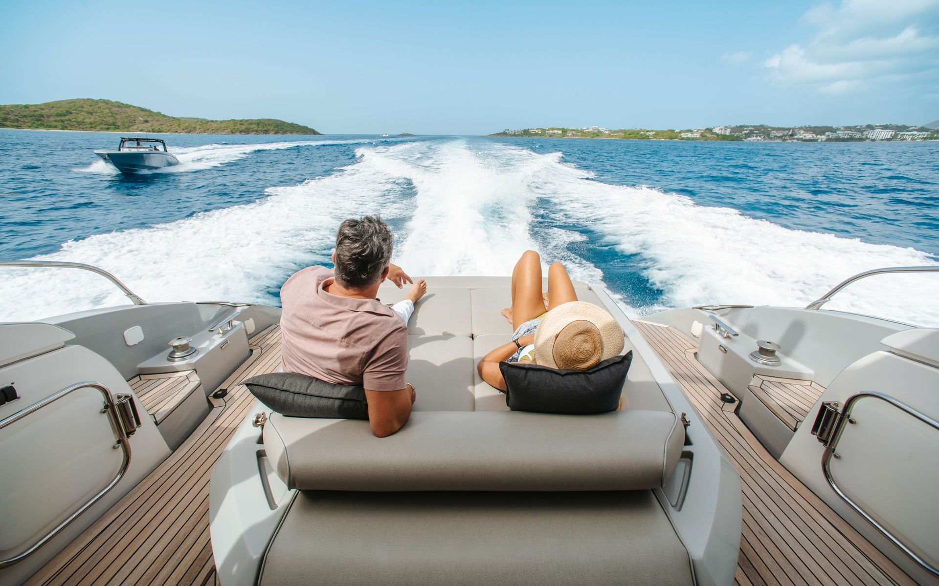 Couple relaxing on a yacht, facing away from the camera, enjoying the ocean view.