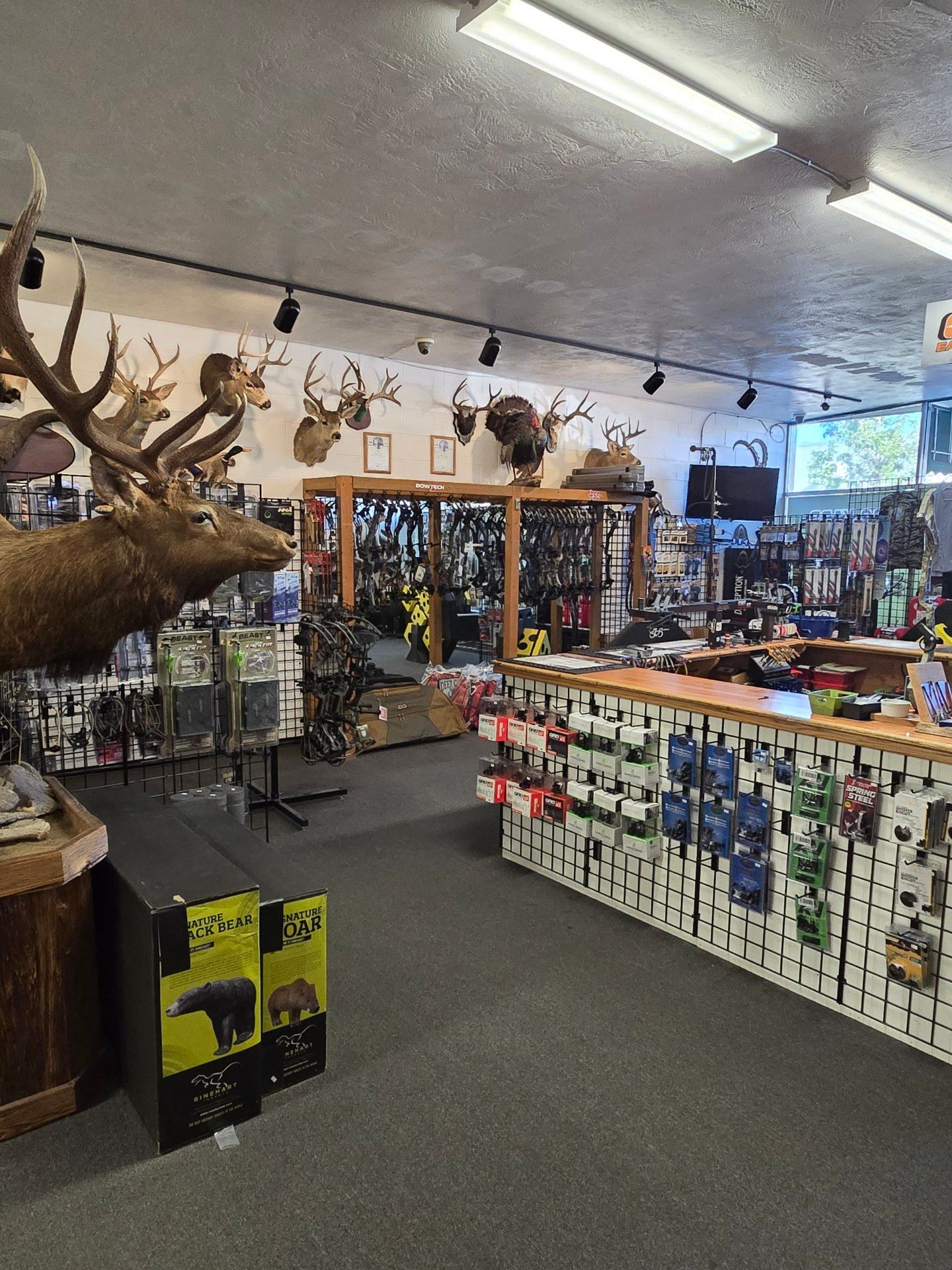 People gathered in an indoor shooting range with targets and firearm stands.