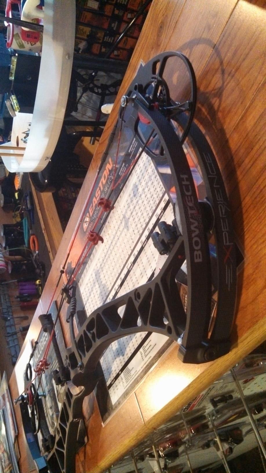 Indoor archery range with a compound bow resting on a wooden table in warm light