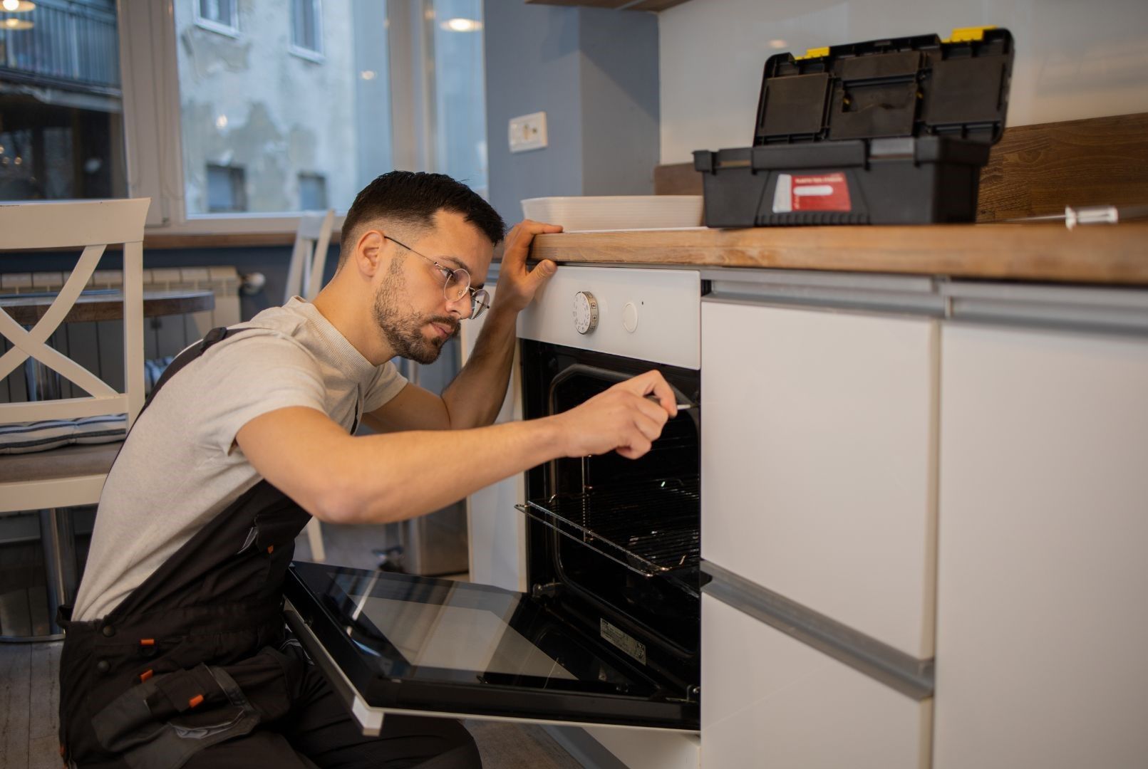 A man is fixing an oven in a kitchen.
