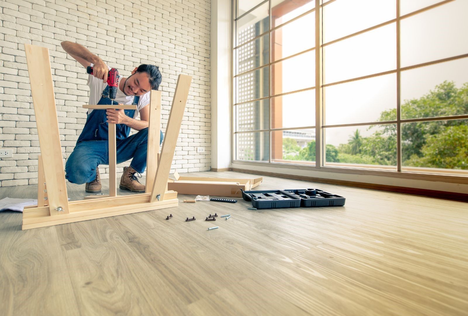 A man is kneeling down to assemble a wooden table.