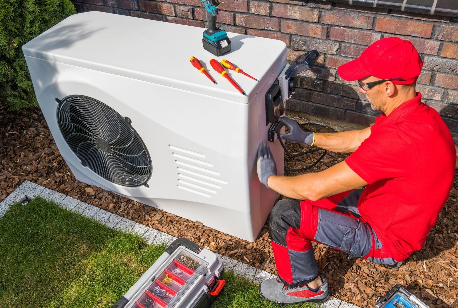 A man is working on an air conditioner outside of a house.