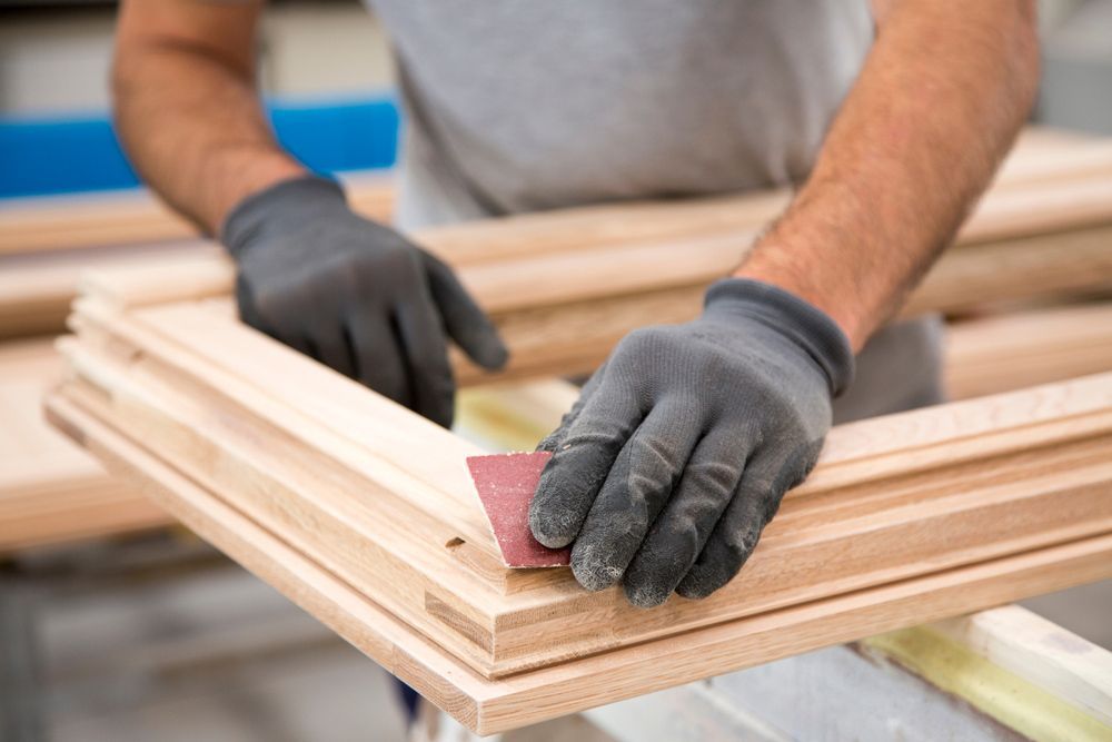 A man is sanding a piece of wood with a sandpaper.