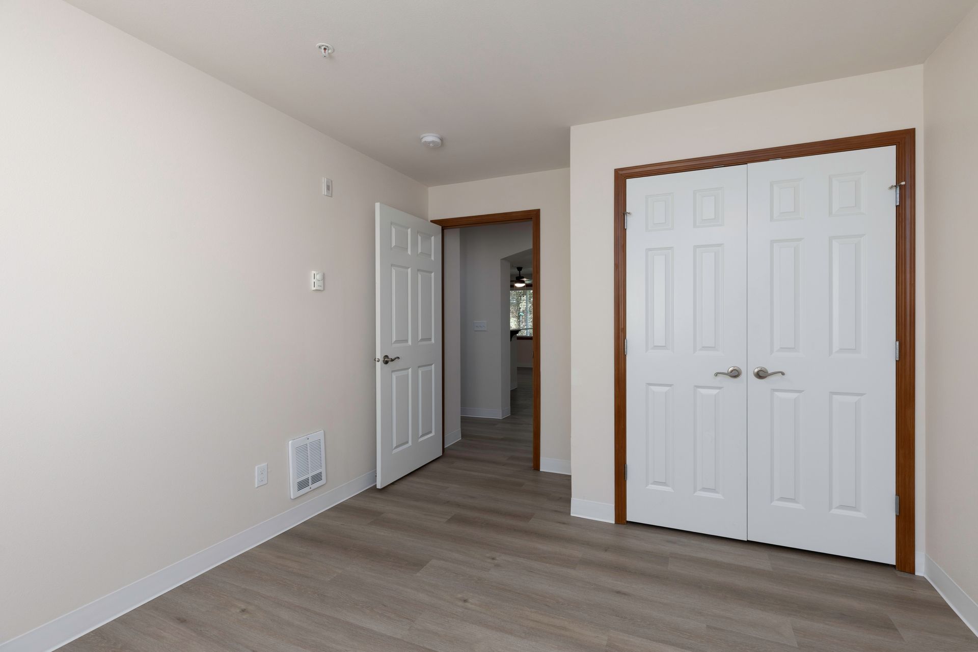 Photo of a bedroom with the room door open and dual closet doors closed