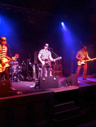 A group of men are on stage playing guitars and singing into microphones