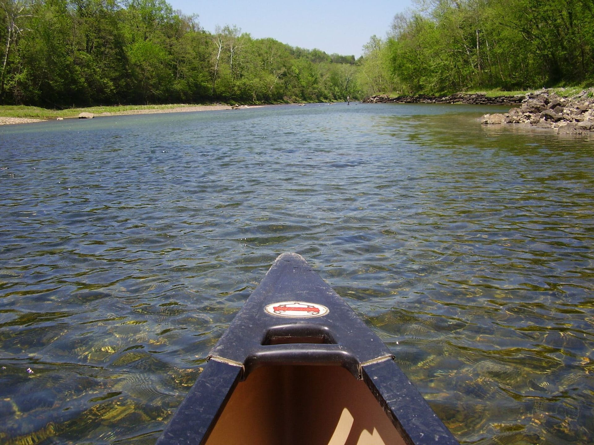 A canoe is floating down a river with trees in the background