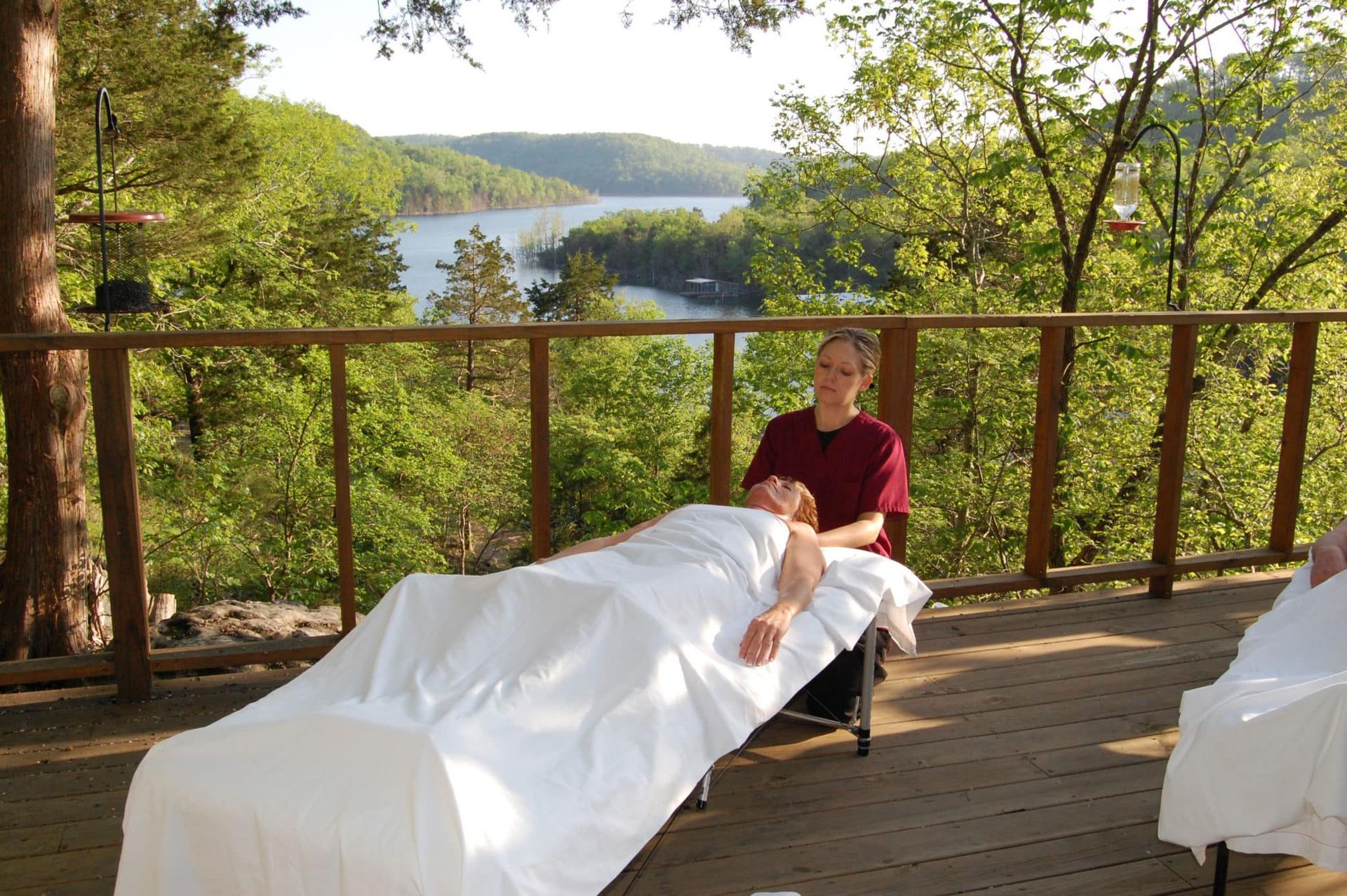 A woman is giving a man a massage on a deck overlooking a lake