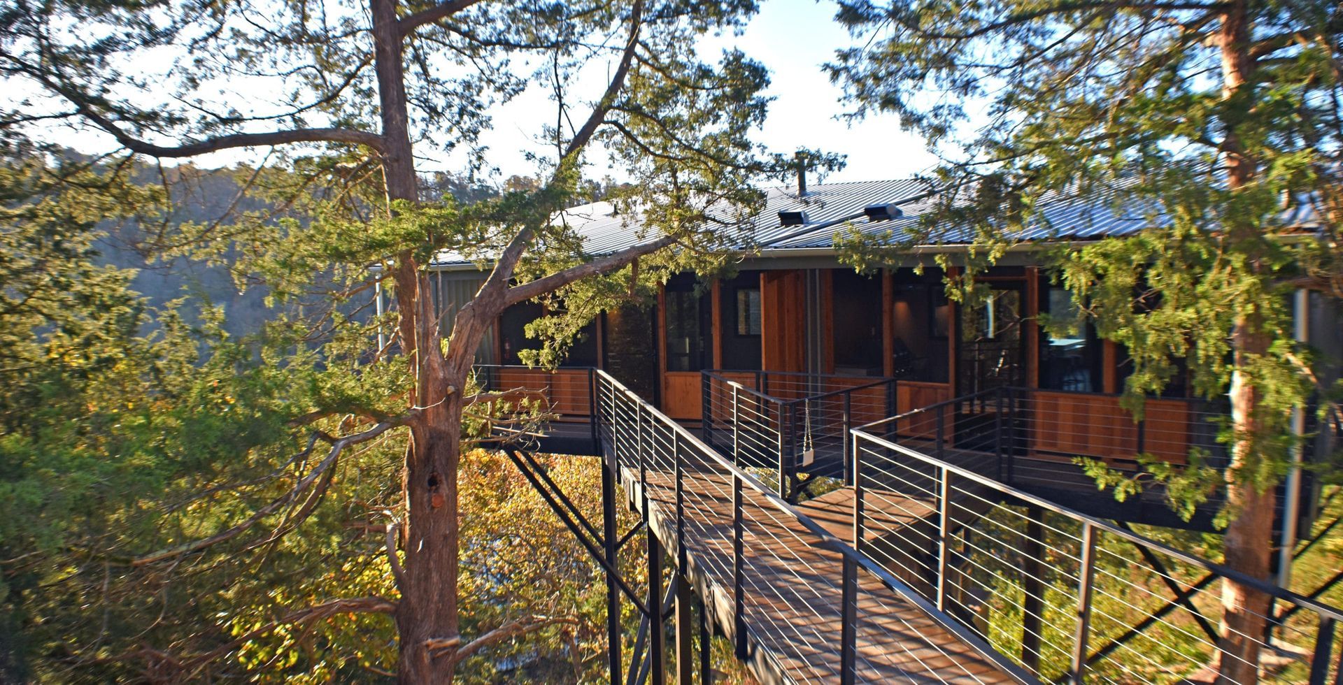 A house with a bridge leading to it is surrounded by trees.