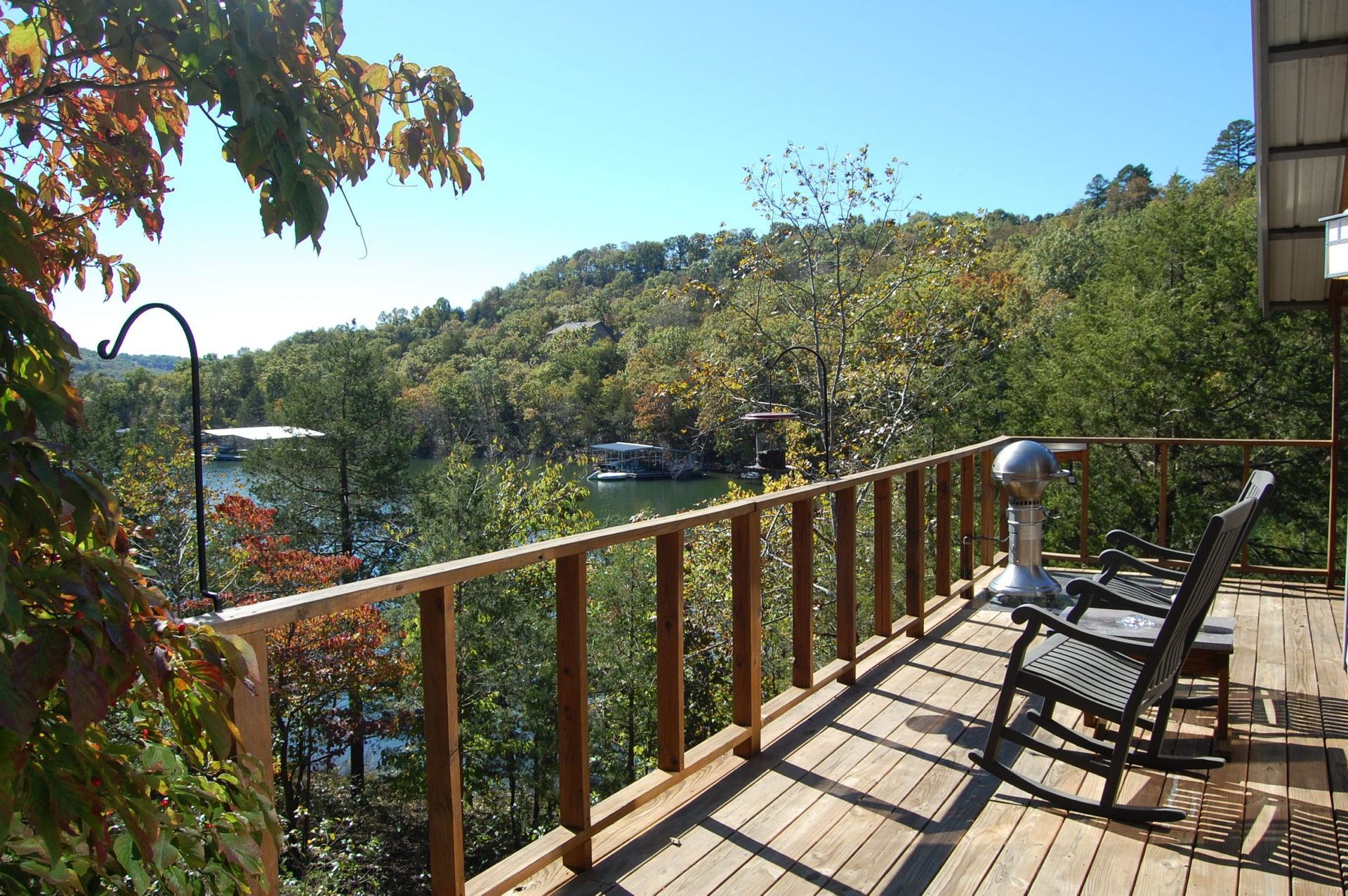 A wooden deck with a railing overlooking a lake and trees.