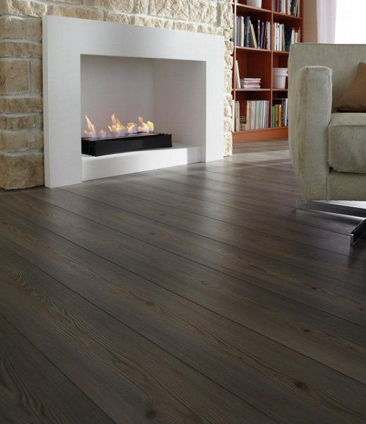 Soggiorno moderno con camino bianco, pavimento in legno scuro e divano beige.