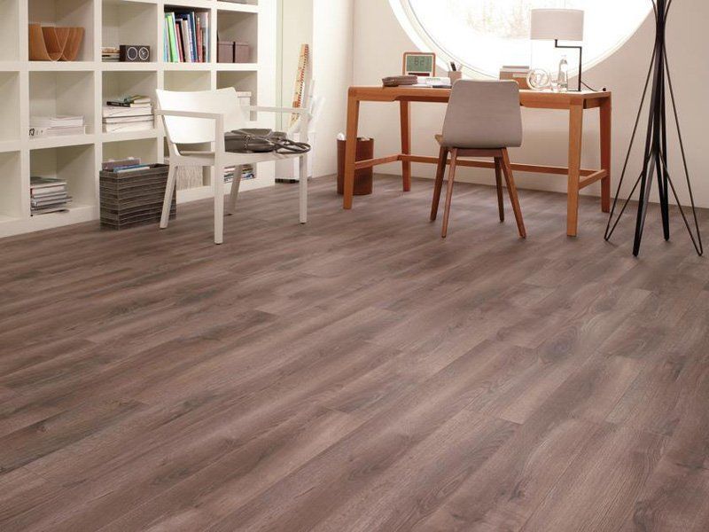 Ufficio domestico minimalista con scrivania, sedia, mensole e pavimento in legno in una stanza luminosa.
