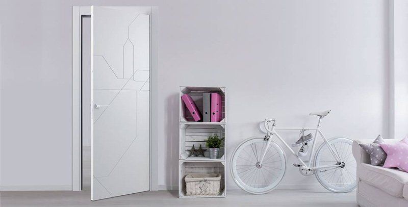 Camera da letto minimalista bianca con porta aperta, piccola mensola, bicicletta bianca e letto con lenzuola rosa.