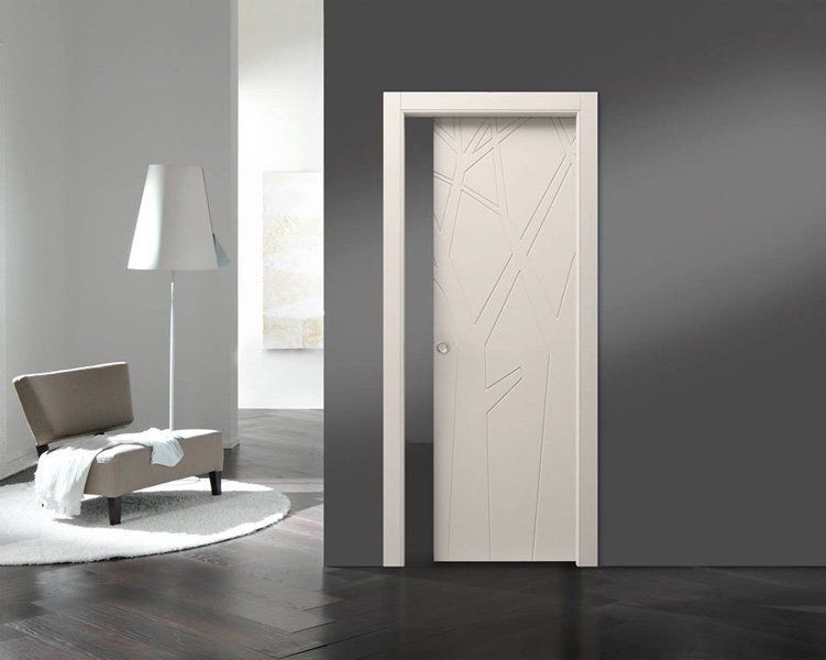 Interno moderno con porta bianca, pareti grigie, lampada da terra e sedia su un tappeto rotondo.
