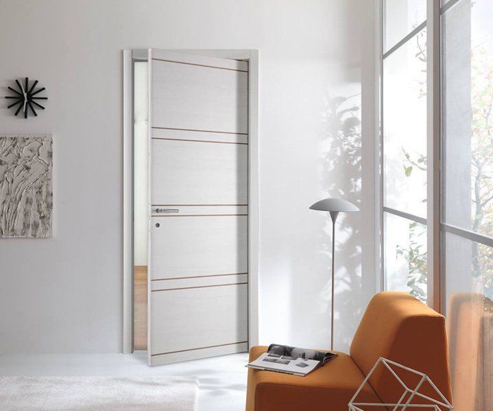 Interno moderno bianco con porta parzialmente aperta, sedia arancione, lampada da terra e grande finestra.