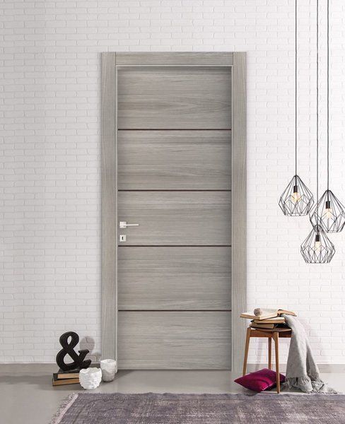 Porta grigia moderna in una stanza minimalista con lampade a sospensione e piccoli dettagli decorativi.