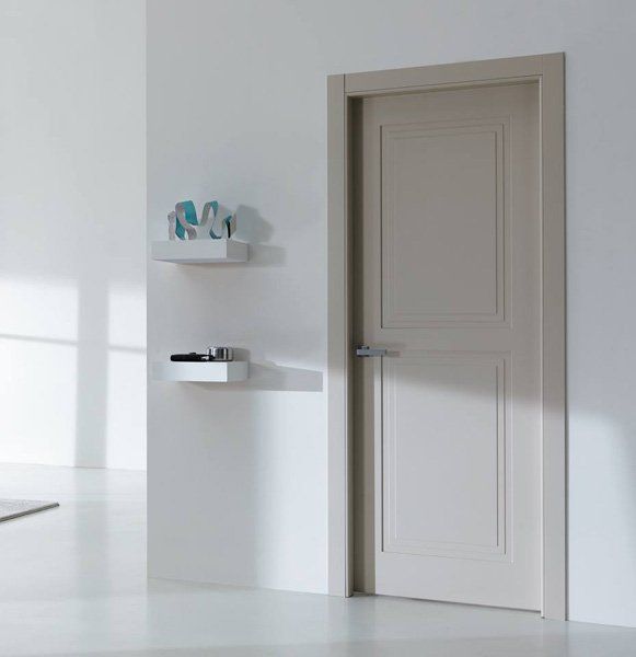 Stanza bianca con porta chiusa e due mensole a muro che ospitano piccoli oggetti decorativi.
