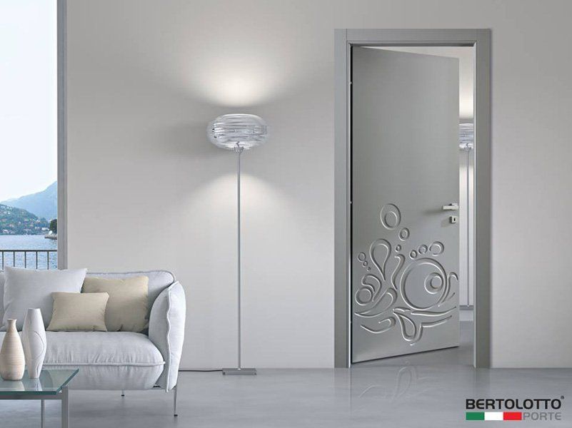 Soggiorno moderno grigio con divano bianco, lampada da terra e porta in vetro satinato con decorazioni floreali.