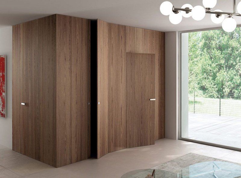 Camera da letto moderna con armadio a pannelli in legno e ampia finestra con vista sul verde.