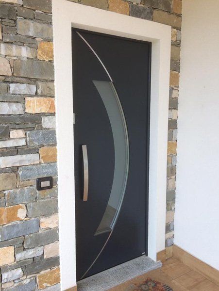 Porta d'ingresso moderna nera con pannelli in vetro satinato in un atrio in pietra.