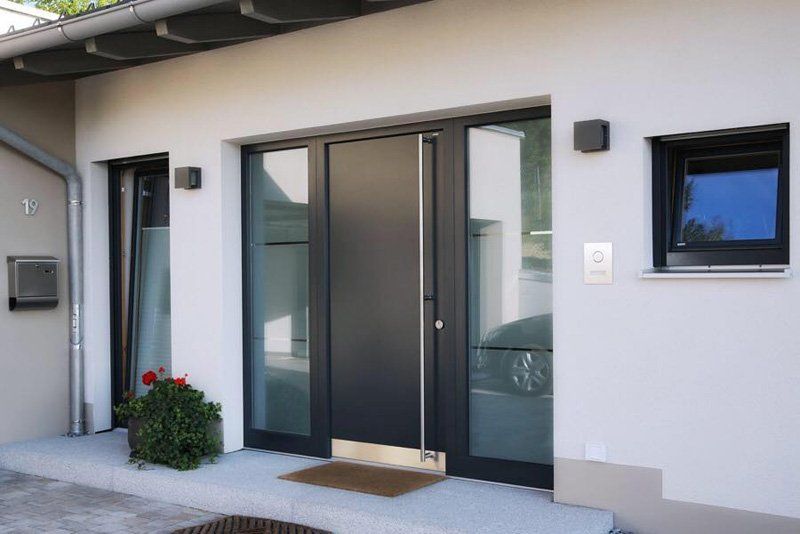 Ingresso di casa moderna con doppie porte a vetri, fiori in vaso e una piccola finestra accanto all'ingresso