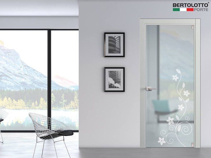 Interno moderno con porta in vetro satinato, quadri incorniciati alle pareti e finestra con vista sulle montagne accanto a una sedia nera.
