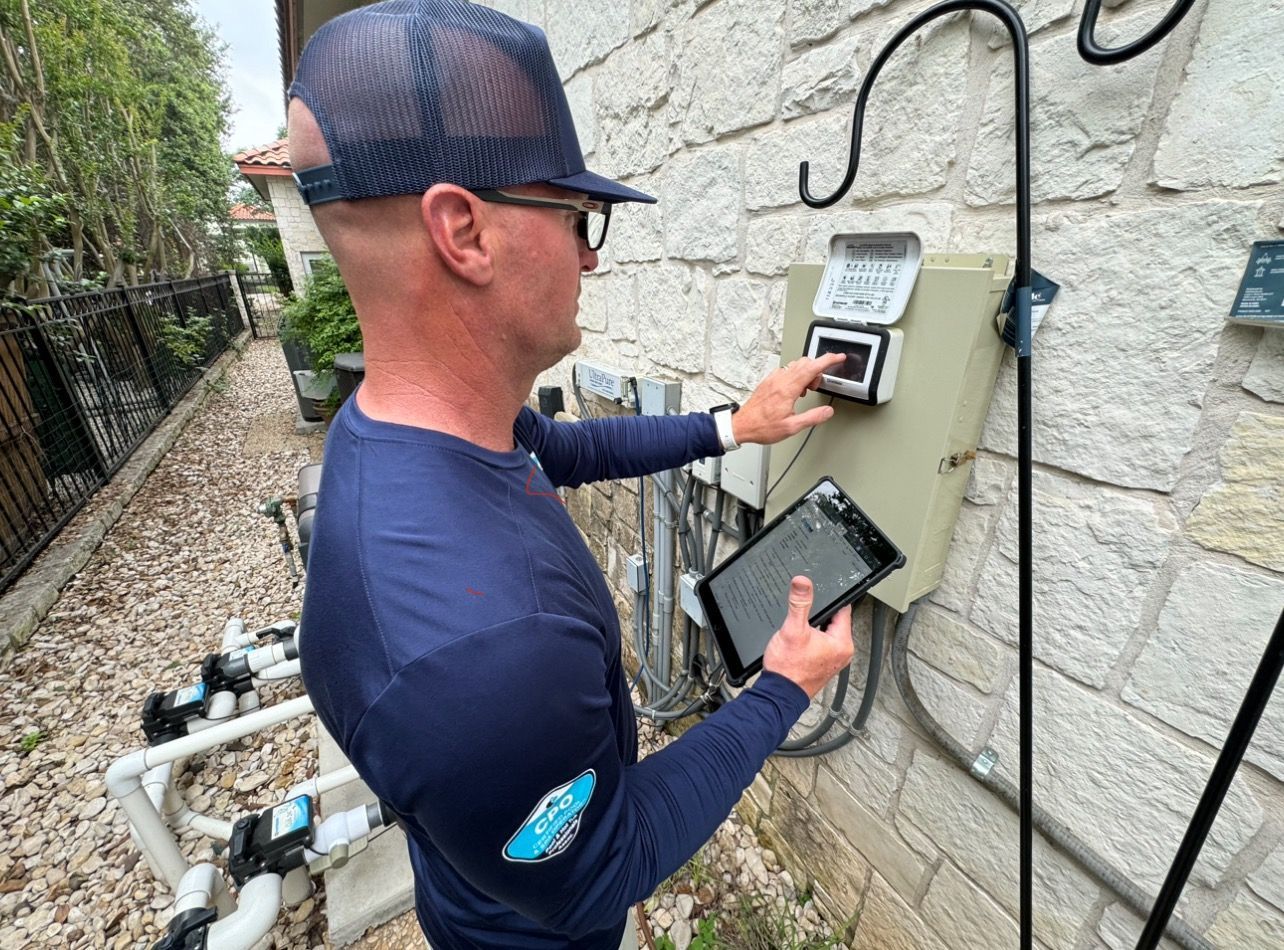Person checking a wall-mounted utility meter with a handheld device outdoors.