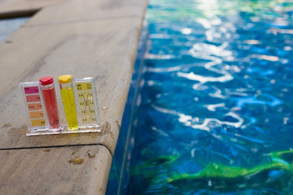 Poolside water test strips beside a blue swimming pool