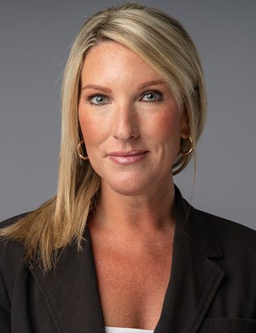 Portrait of a woman in a black blazer against a gray background