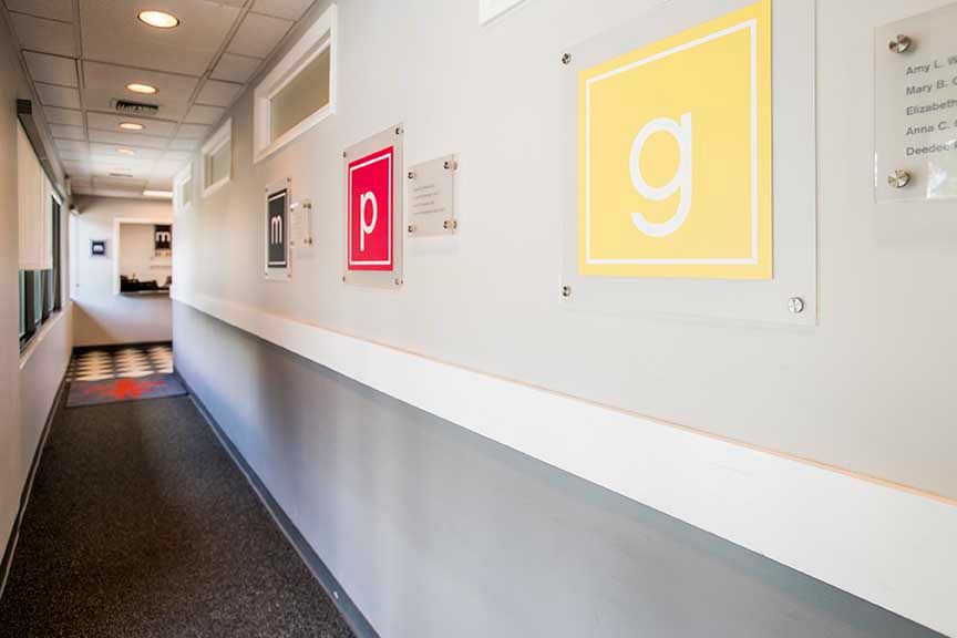 Hallway with colorful square signs on the wall, including red and yellow letters, in a modern office or school.