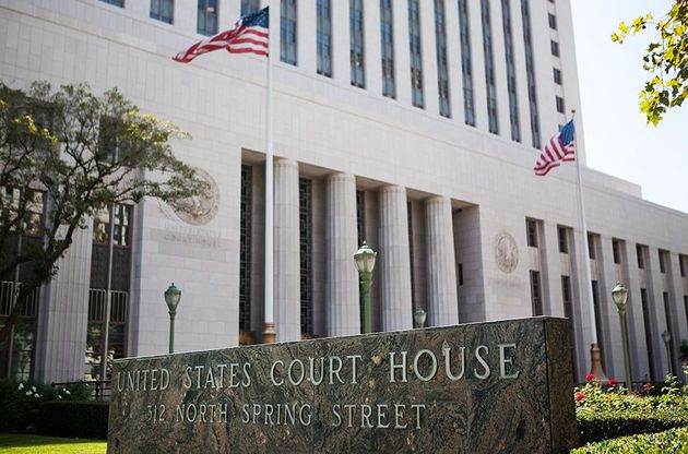 U.S. courthouse with white columns, American flags, and a stone sign at the entrance