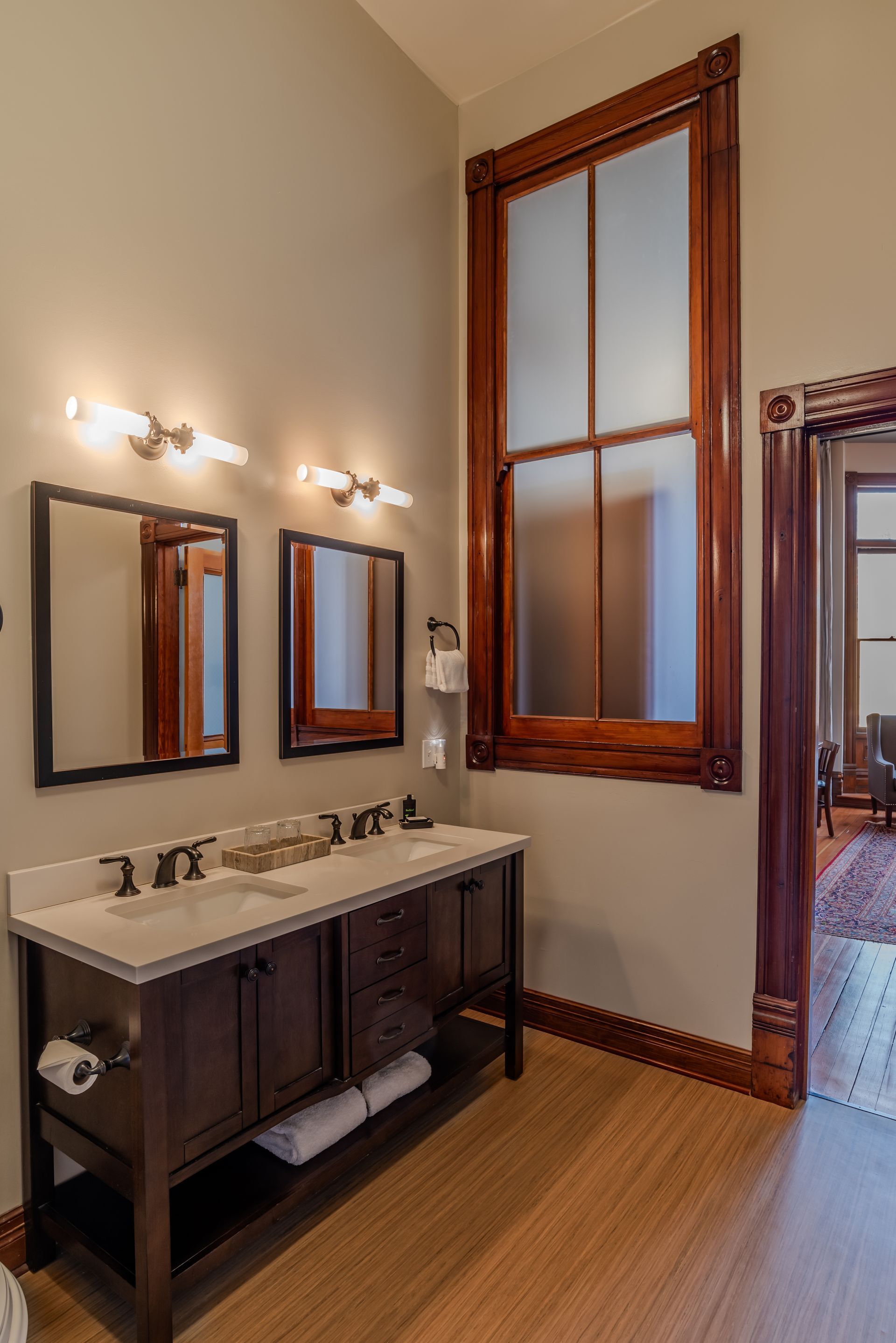 A bathroom with two sinks , two mirrors and a large window.