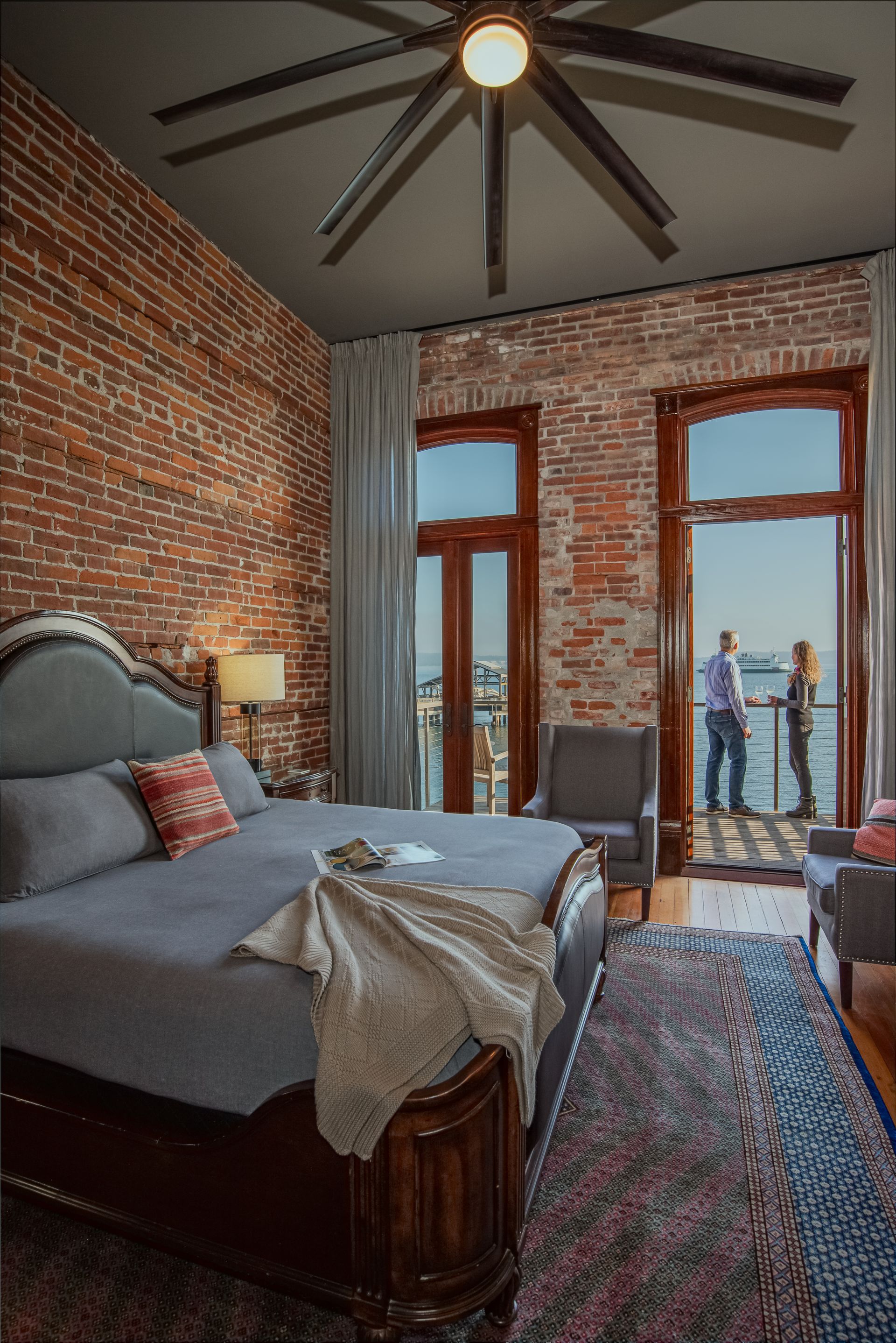 A bedroom with a large bed and a balcony overlooking the water.