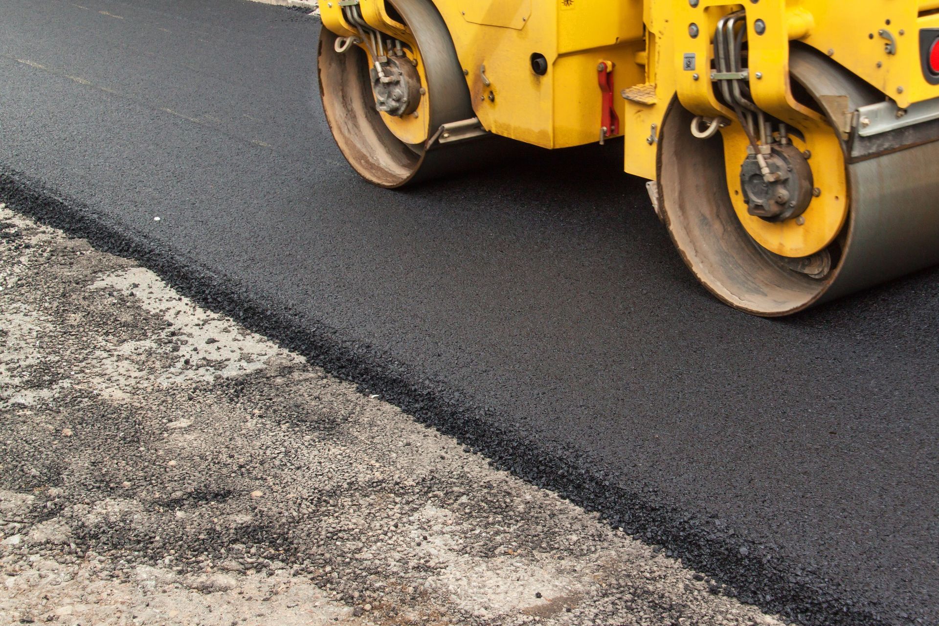 Asphalt paving machine compacting fresh blacktop on a roadway during road resurfacing work