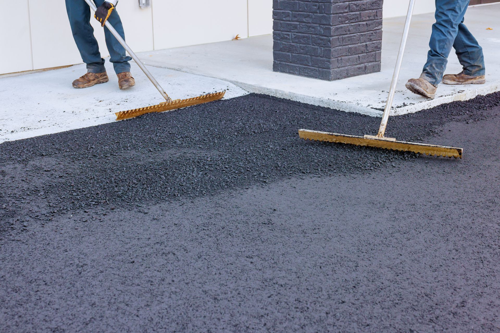 Expert team from a local paving contractor smoothing asphalt surface for a commercial lot.