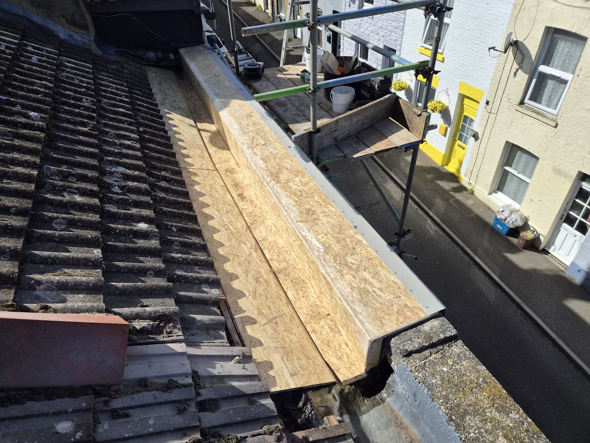 Scaffold view of new timber roof-edge boxing and preformed GRP trim above a terraced street in Ramsgate