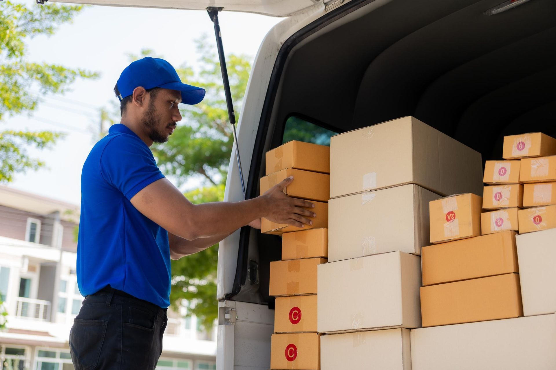 Delivery worker loading cardboard boxes into a van outdoors