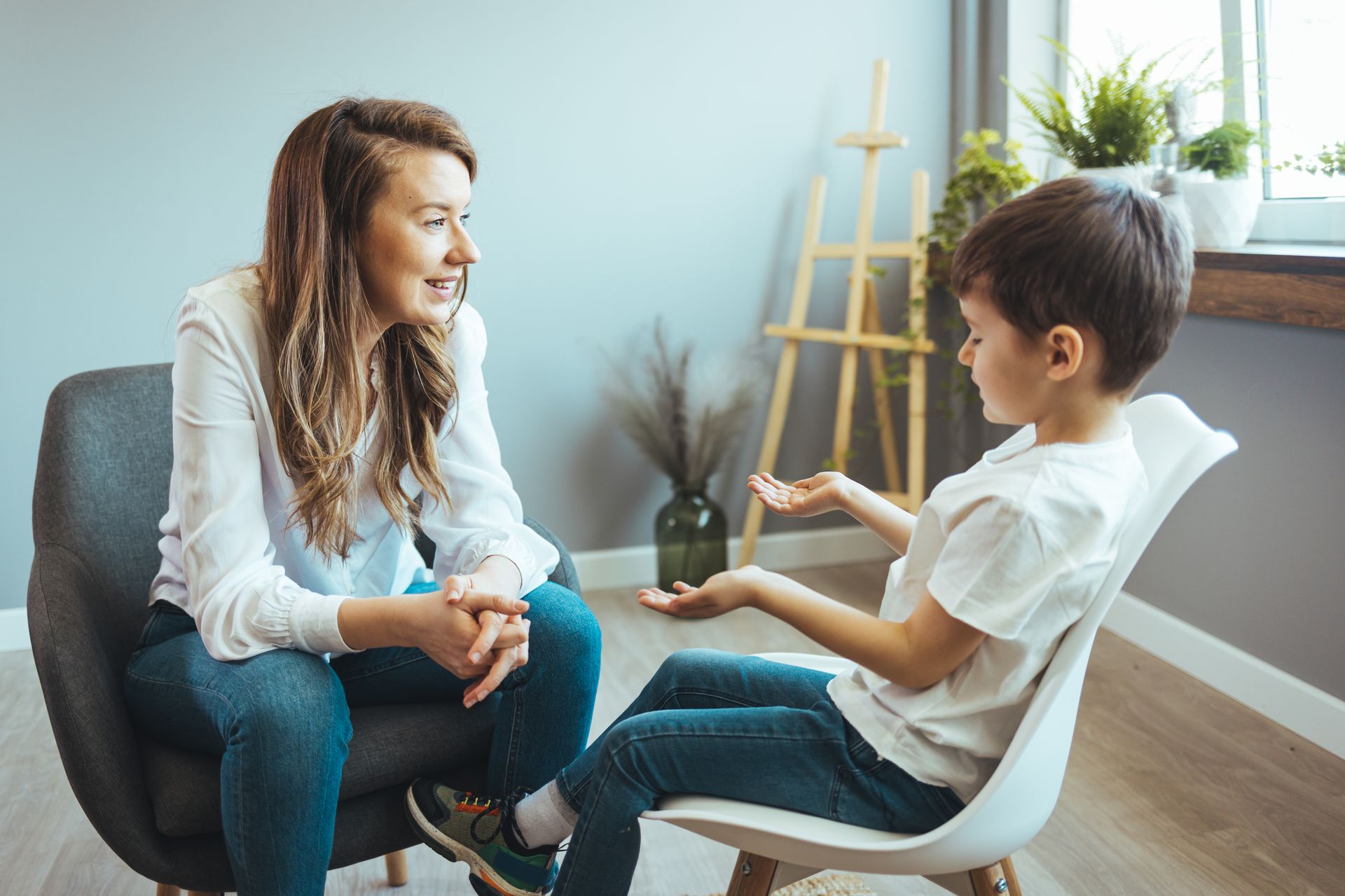Therapist talking with a child in a bright counseling room, seated facing each other.