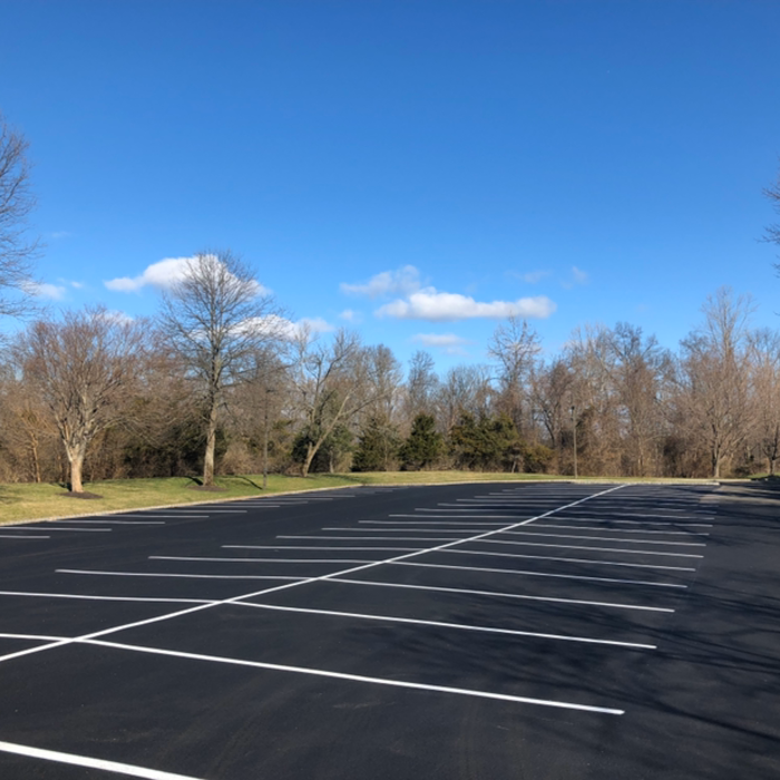 Yellow painted lines and symbols on asphalt: parking spaces with accessible symbol and arrow.