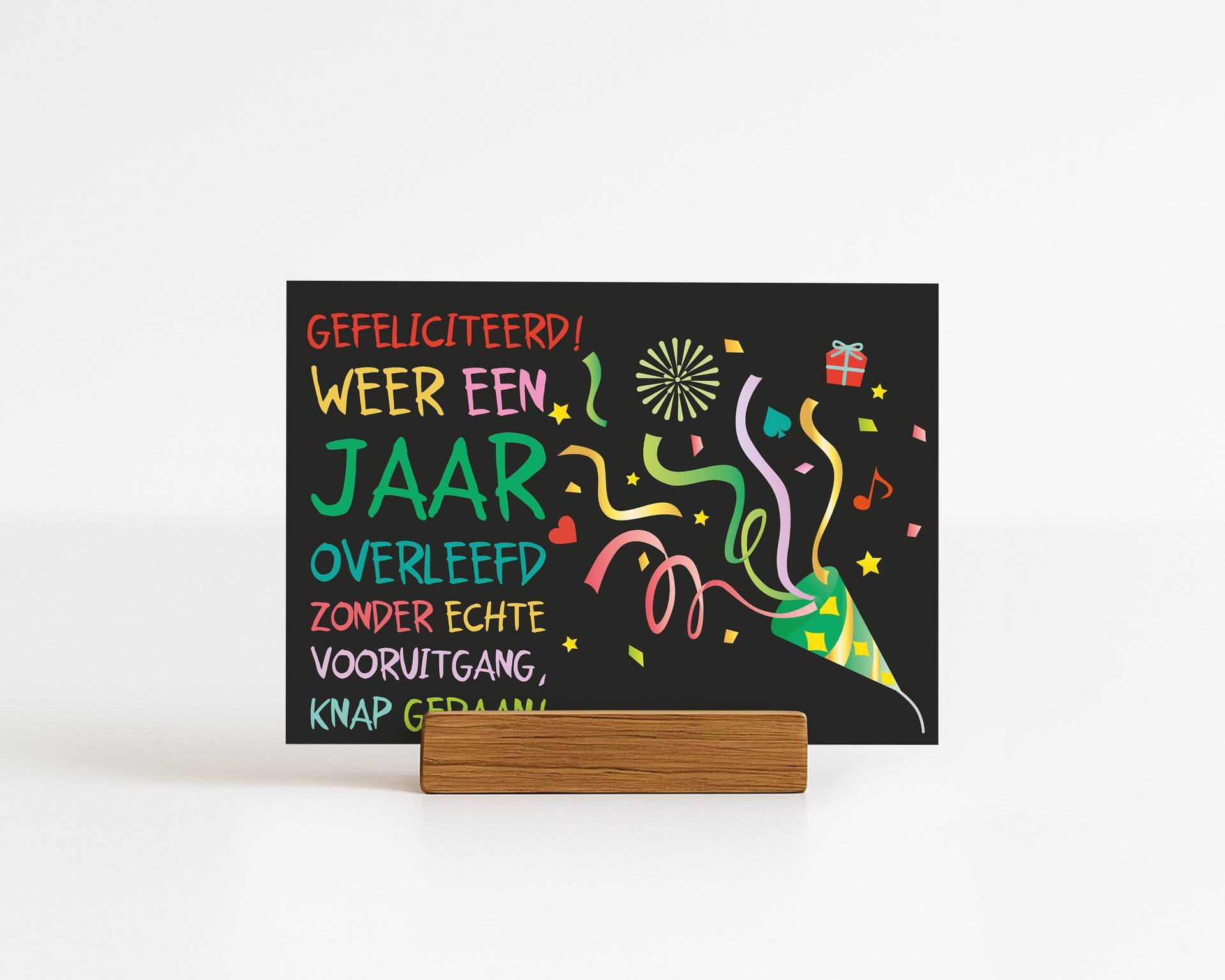 Black sign with birthday message and confetti, in wooden stand.