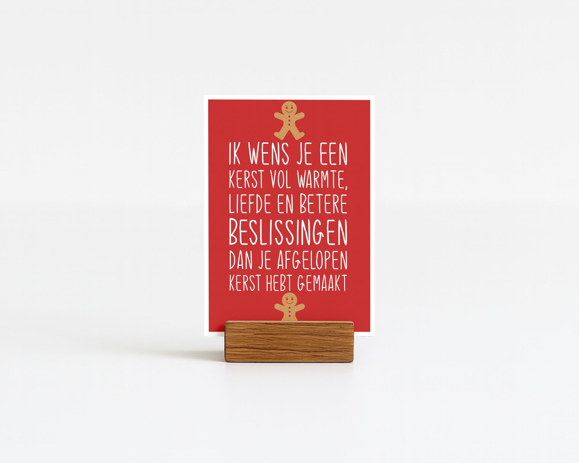 Red card with Dutch text in a wooden holder, two gingerbread man figures, white background.