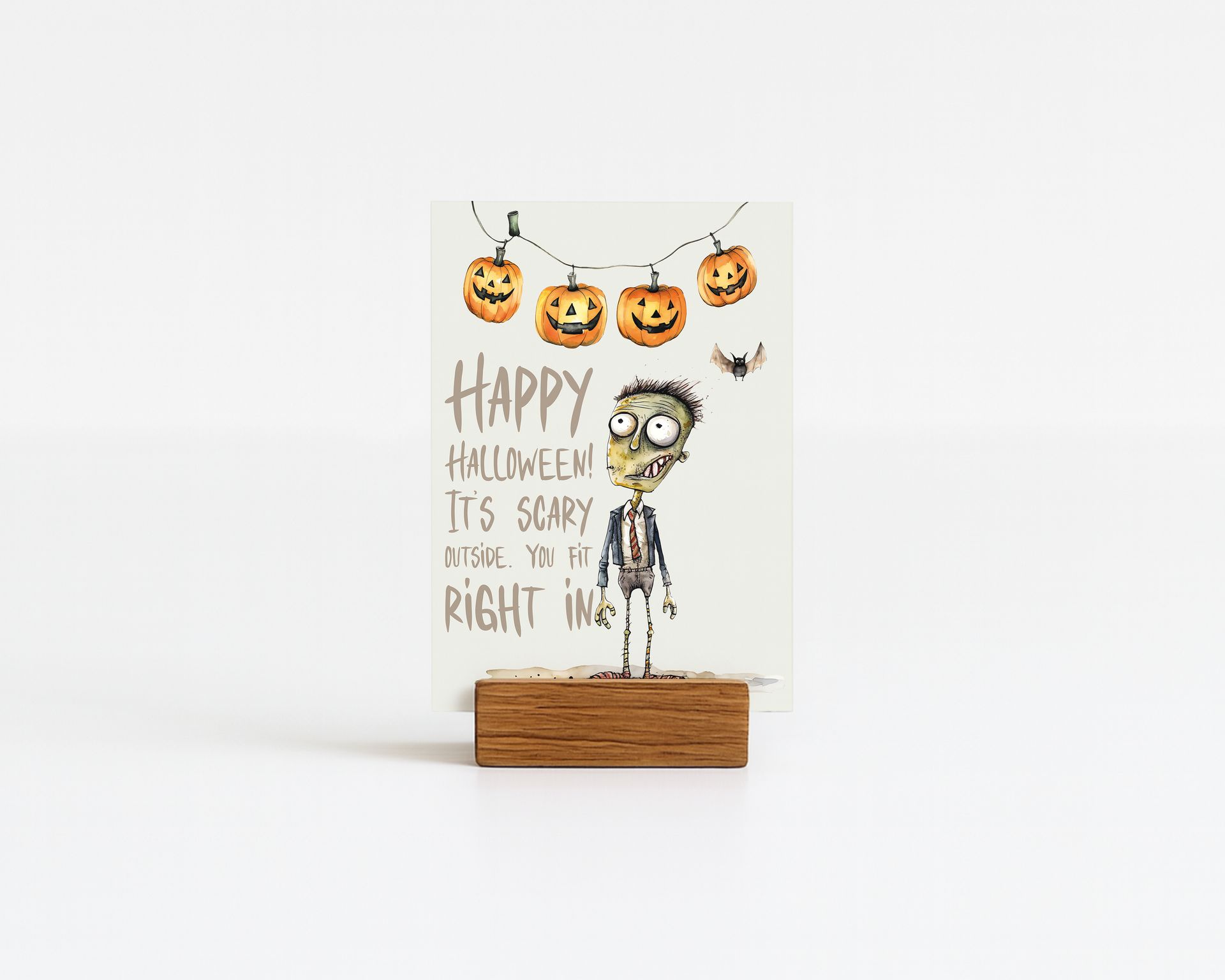 Halloween greeting card with zombie illustration, pumpkins, and lights, held in a wooden stand.