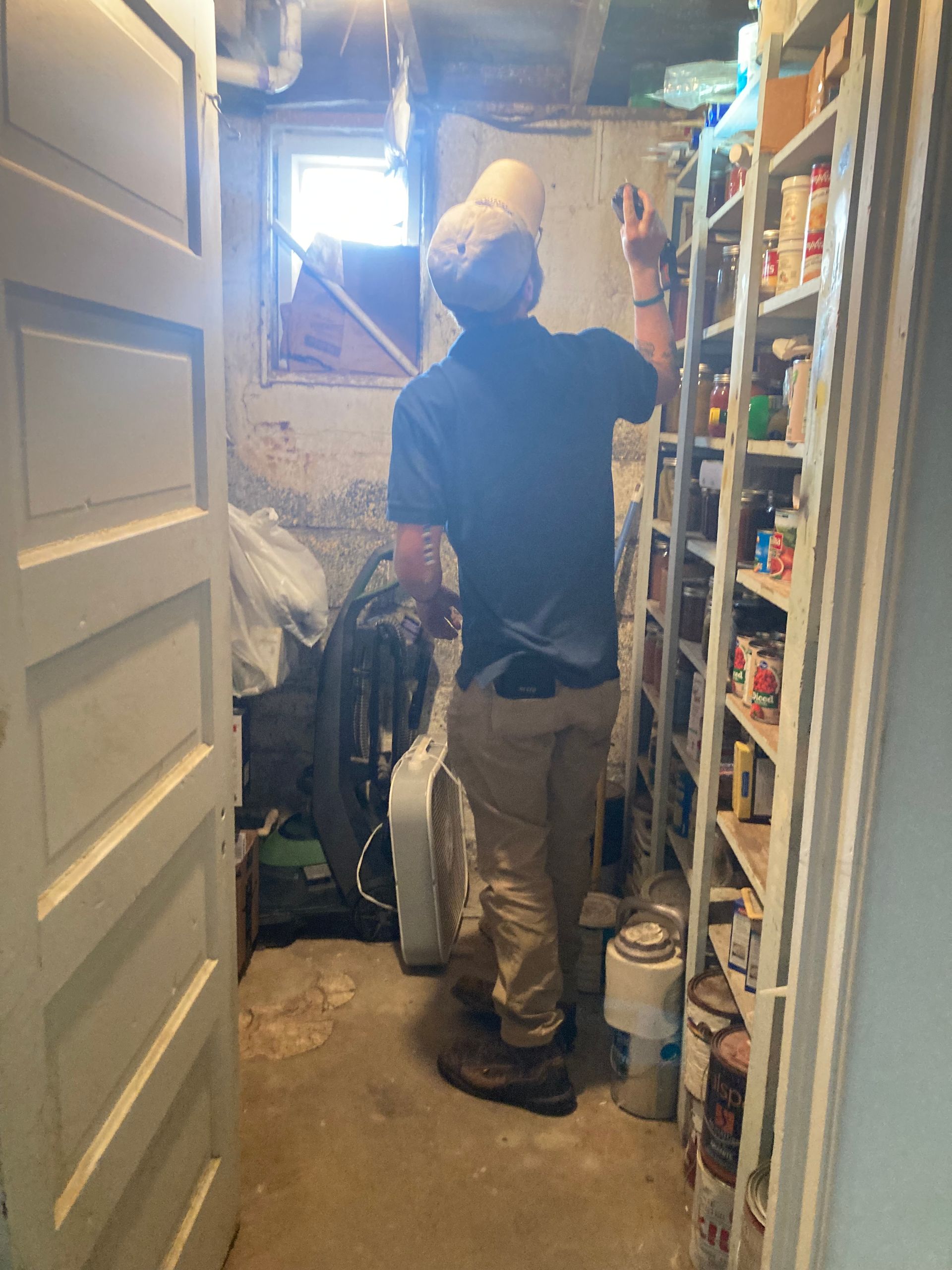 A man is standing in a room filled with shelves and buckets of paint