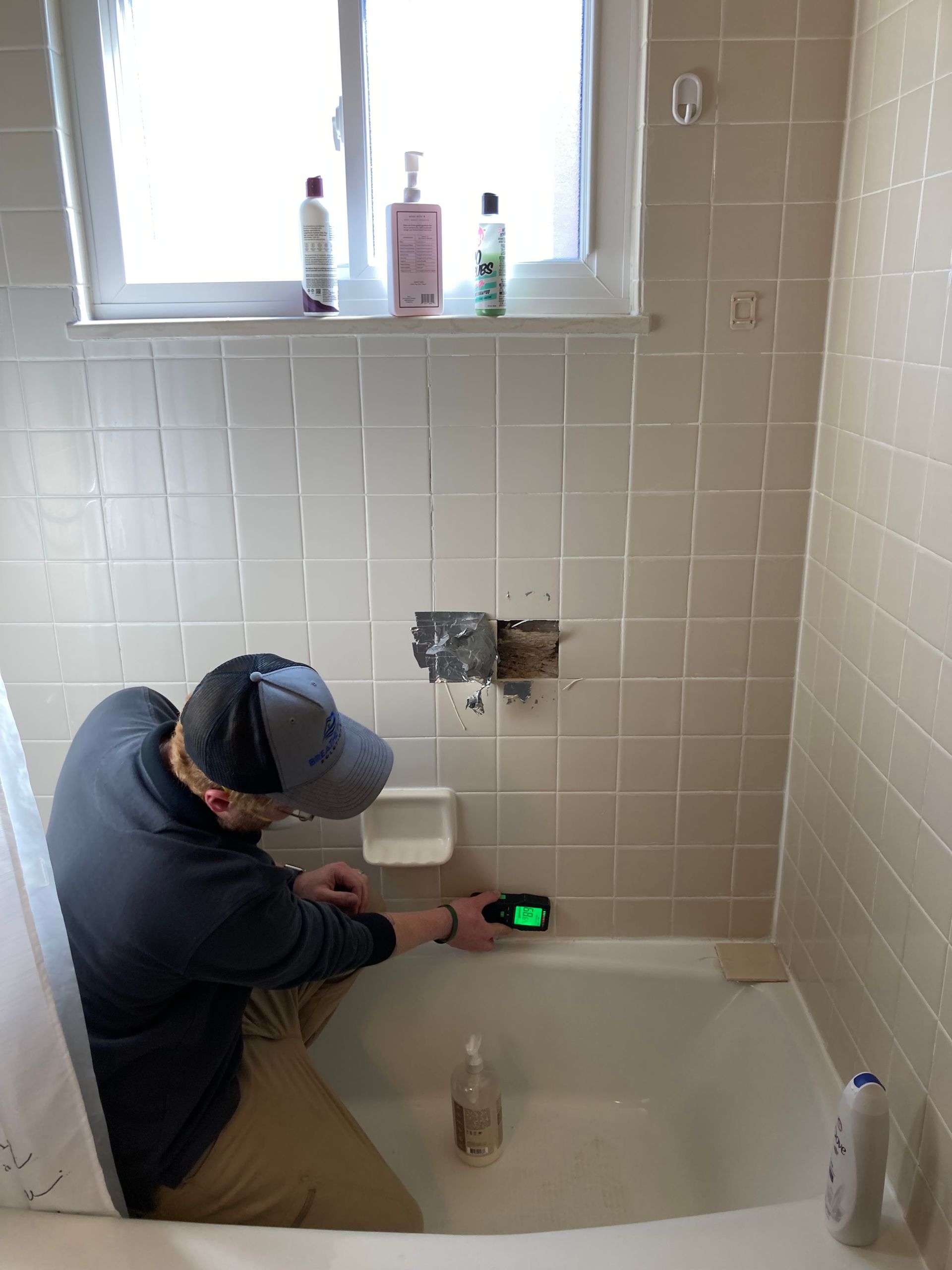 A man is kneeling in a bathtub in a bathroom.