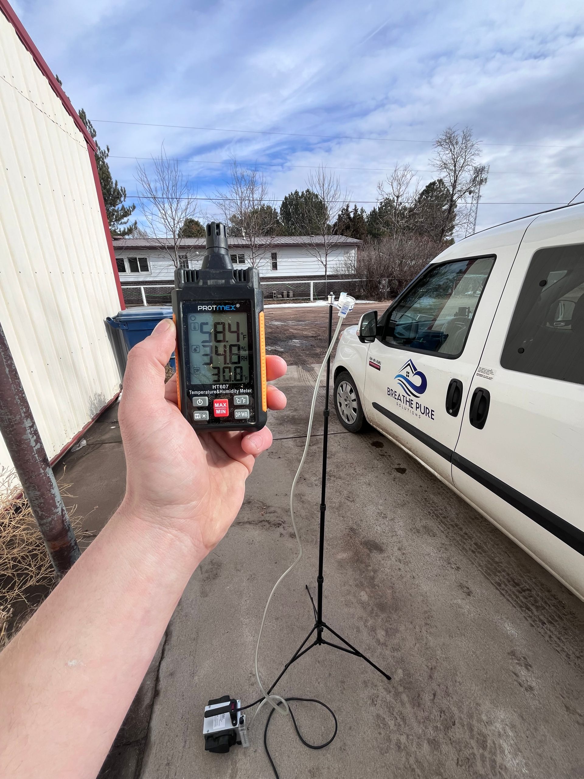 A person is holding a device in front of a white van.