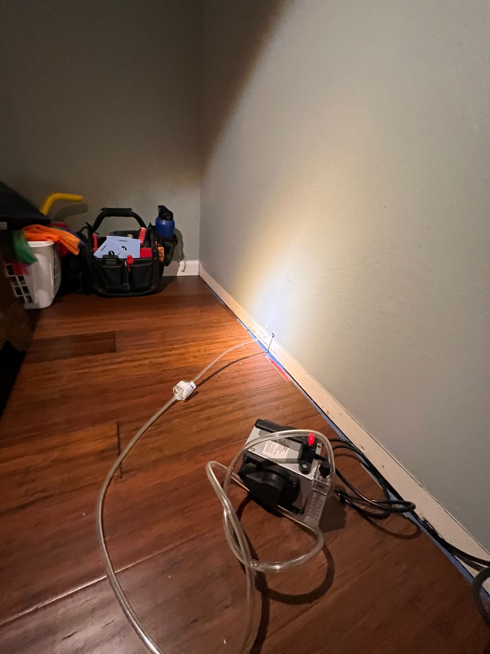 A vacuum cleaner is sitting on a wooden floor next to a wall.