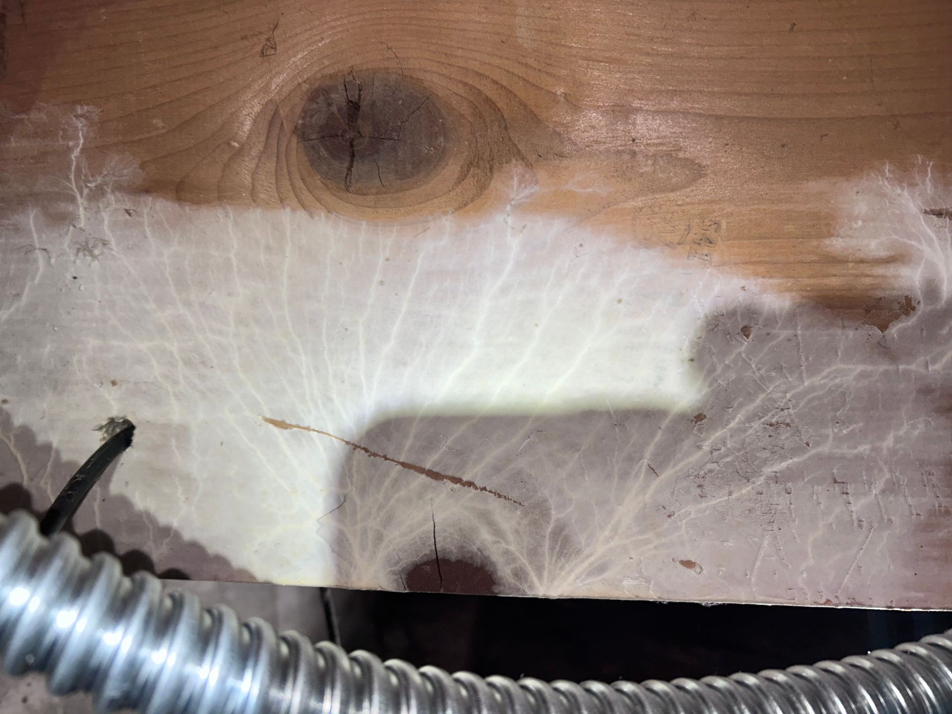 A close up of a wooden floor with a metal hose attached to it.