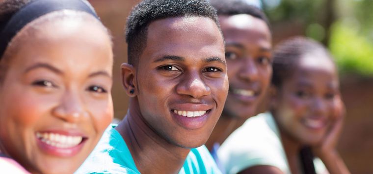 Four smiling people outdoors, with a man centered in the foreground