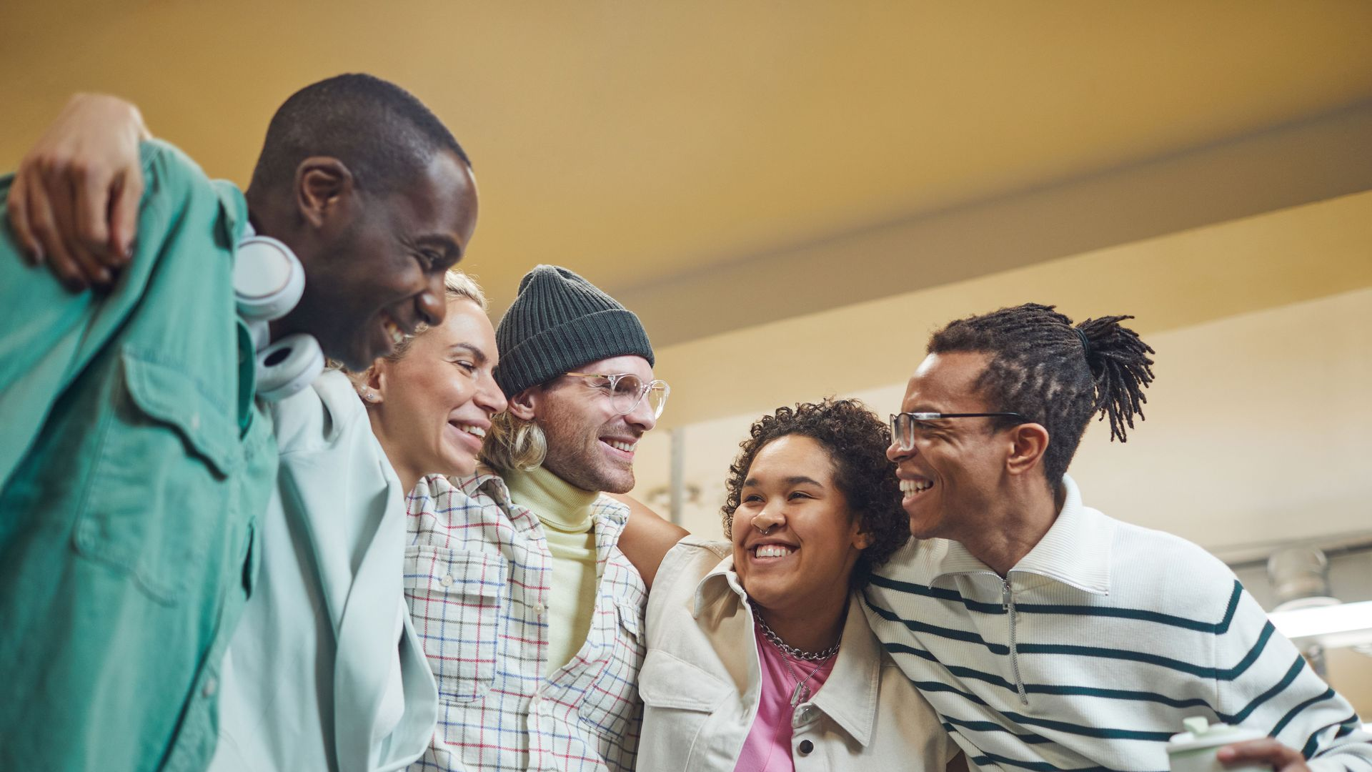 Five friends smiling and leaning together in a bright indoor setting