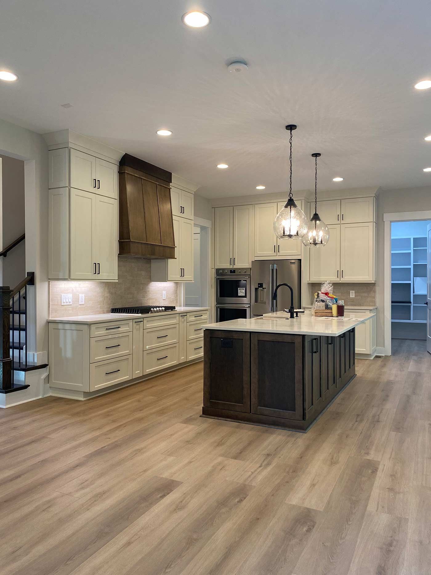 Bright modern kitchen with white cabinets, wood island, pendant lights, and wide plank flooring