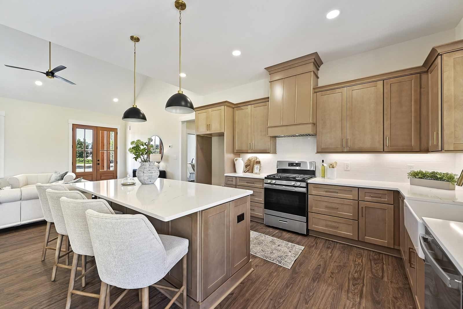 Bright modern kitchen with white island, wood cabinets, pendant lights, and hardwood floors